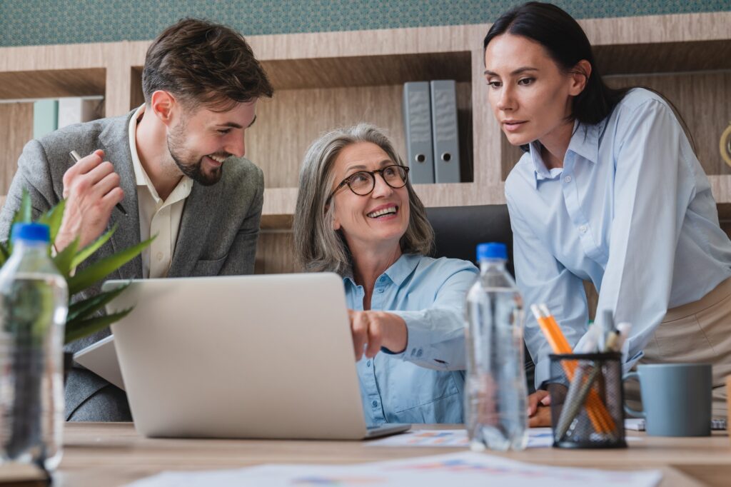 Team Collaborating Around Laptop in Modern Office Environment